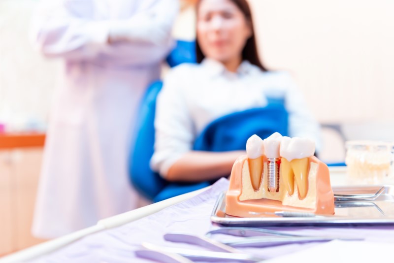 a dental implant patient looking at a dental implant model.