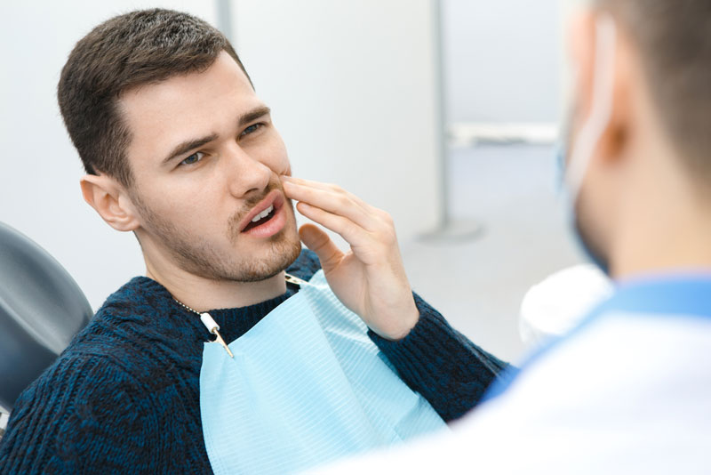 dental patient suffering from pain sitting in a dental chair.