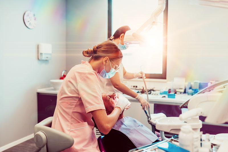 two nurses help place implants in a dental patient.